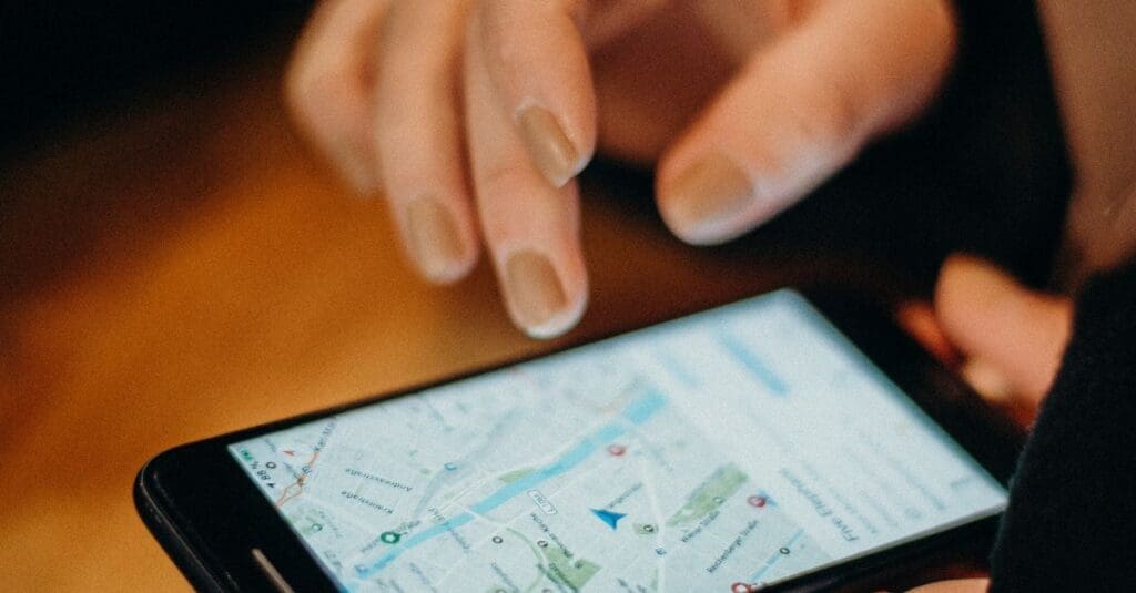 Close-up of someone tapping a smartphone screen displaying a map with a blue location pin and route markers.